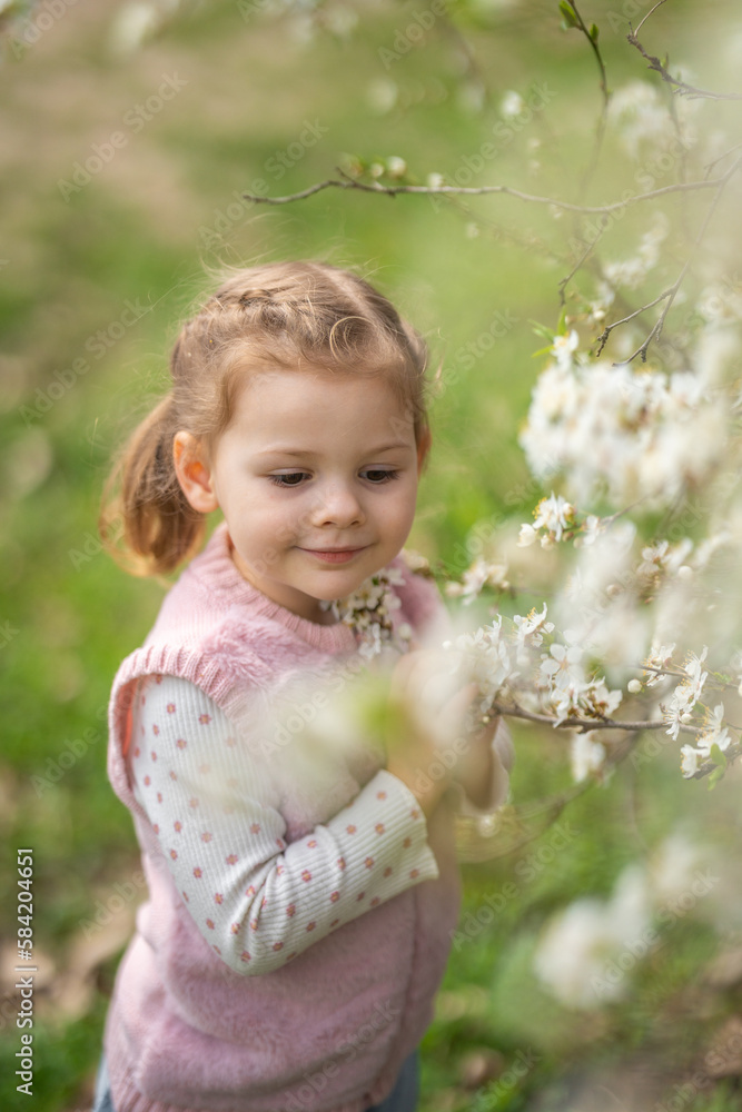 Little girl enjoying nice and sunny spring day near blooming apple tree in Prague park Little girl enjoying nice and sunny spring day near blooming apple tree in Prague park