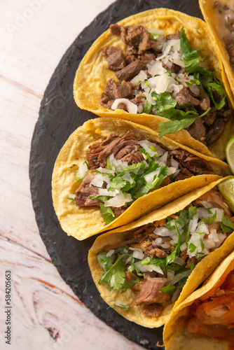 Tacos mexicanos sobre pizarra negra y mesa de madera (ID: 584205653)