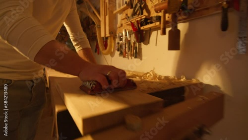 Close-up of a man hand filing a wooden board made by him in a home workshop photo