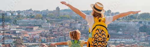 View from behind of Young red-haired mother and little daughter raised thair hands up against the Porto city, Portugal