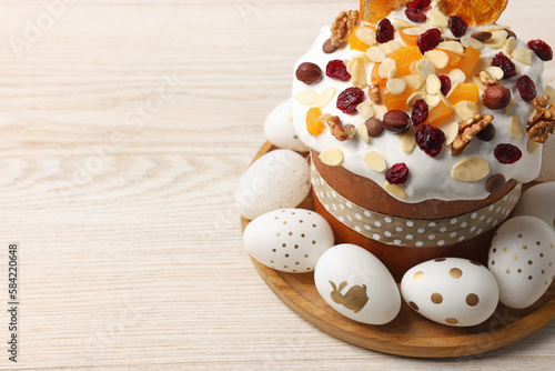 Traditional Easter cake with dried fruits and decorated eggs on white wooden table, closeup. Space for text