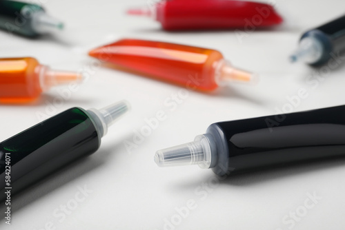 Tubes with different food coloring on white background, closeup