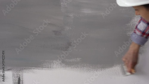 Brush Painting, Female worker painting on surface wall painting apartment, renovating with gray color paint.