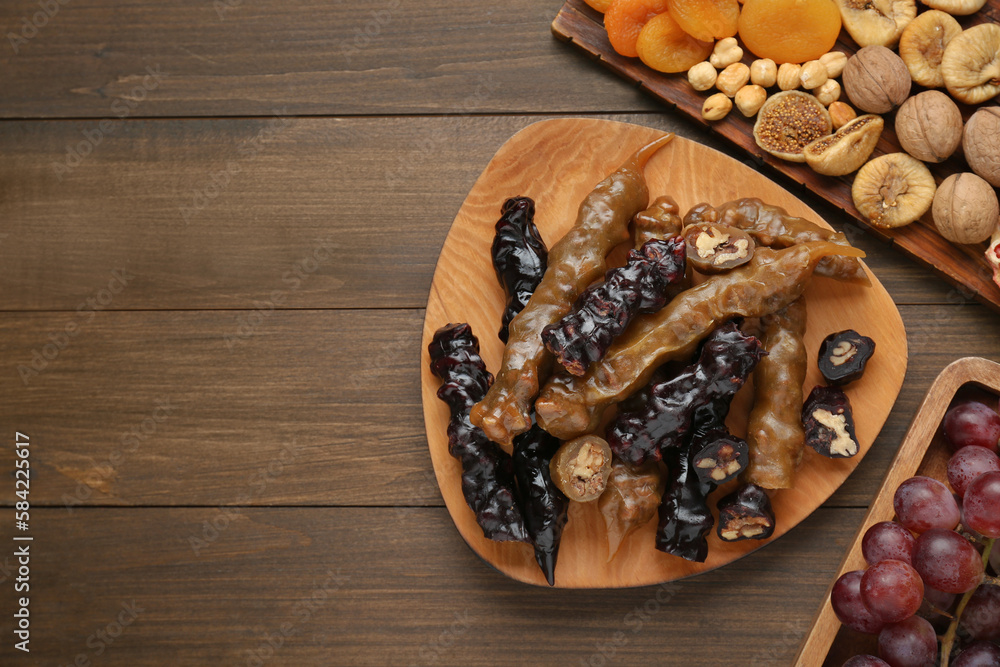 Delicious sweet churchkhelas and ingredients on wooden table, flat lay. Space for text Delicious sweet churchkhelas and ingredients on wooden table, flat lay. Space for text