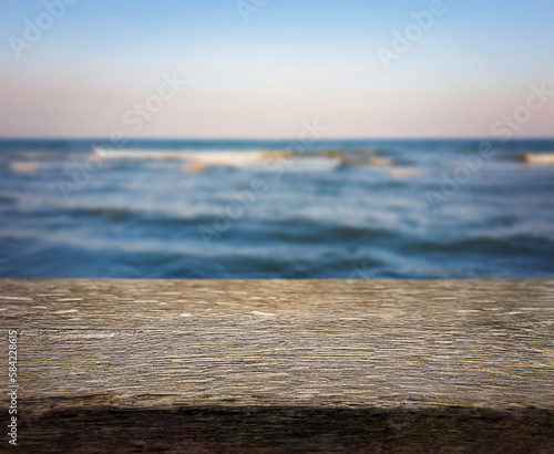 Natural, abstract, unfocused background. Seascape. An empty wooden base, a wooden table, a tabletop against the background of sunset, dawn on the seashore. Copy space