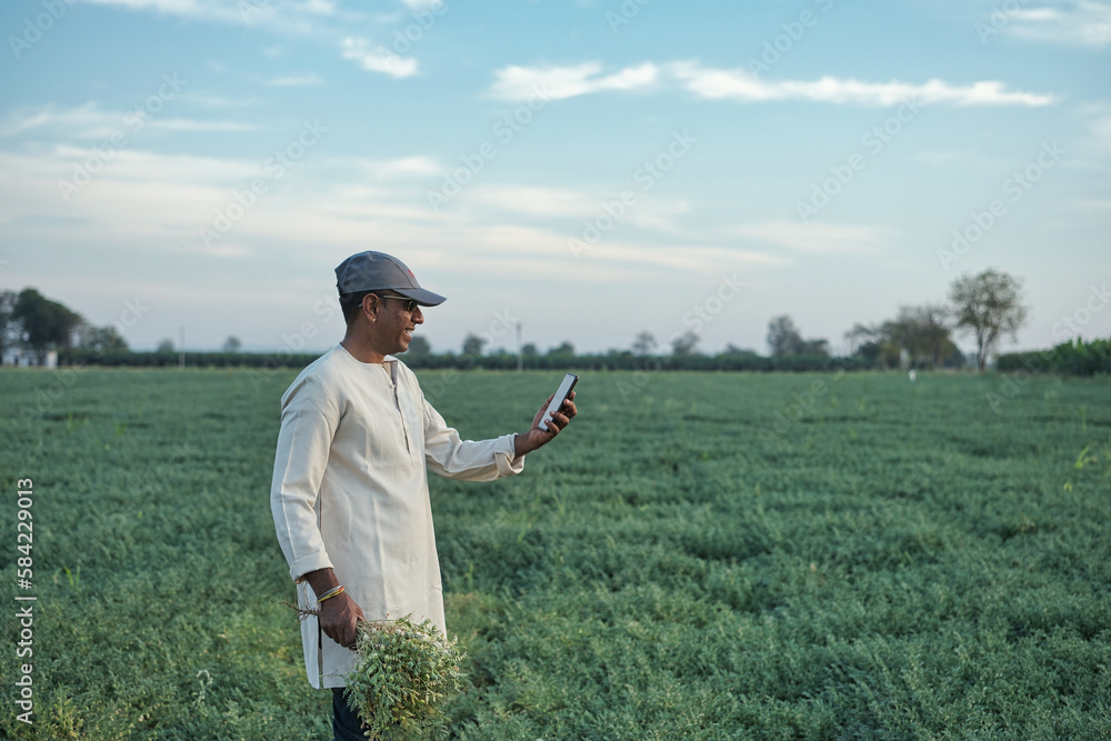 Happy young farmer standing and smiling in his field. 
0shallow depth of field, follow focus, blur.

