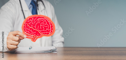 Quadro su tela A doctor holding a brain symbol made from red paper while sitting at the table i