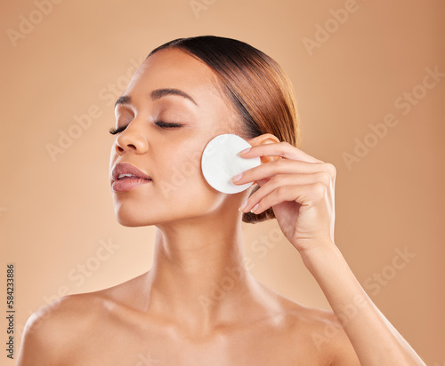 Skincare, cotton and woman in studio for cleaning, wellness and toner on brown background. Face, beauty and girl model with facial pad for makeup removal, glowing skin or aesthetic while isolated