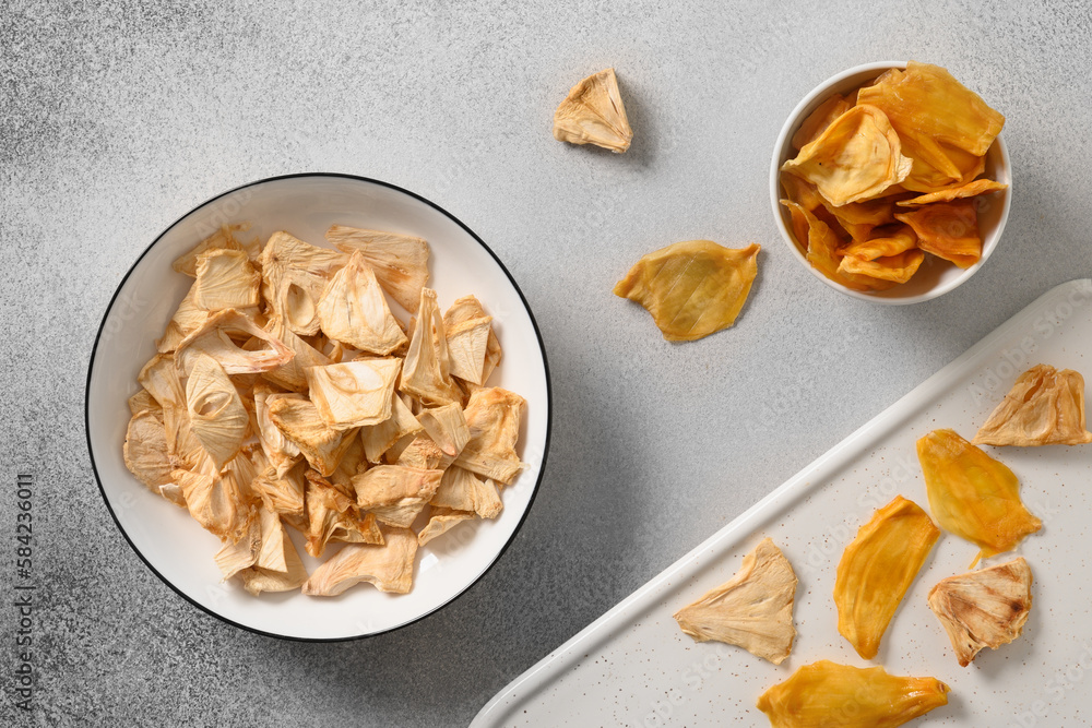 Organic dried Soursop and Jackfruit chips in white plate on gray background. Fruits chips sugar free with antioxidant, vitamin from Sri Lanka. Top view. Organic dried Soursop and Jackfruit chips in white plate on gray background. Fruits chips sugar free with antioxidant, vitamin from Sri Lanka. Top view.