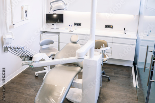 Leather dental chair with various medical instruments located in white dentist office