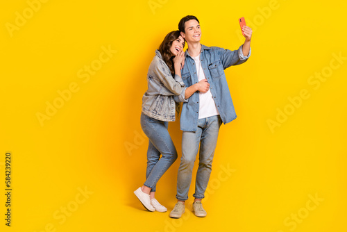 Full length photo of dreamy cute best friends dressed denim tacking selfie modern gadget isolated yellow color background