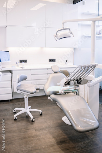 Interior of contemporary tidy dental clinic with white chair and white furniture equipped with modern dental machine and instruments © Ignacio Ferrándiz