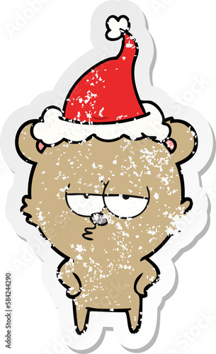 bored bear distressed sticker cartoon of a wearing santa hat