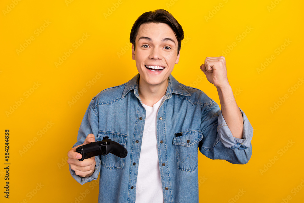 Portrait of delighted funky person hold controller raise fist celebrate win video game isolated on yellow color background Portrait of delighted funky person hold controller raise fist celebrate win video game isolated on yellow color background