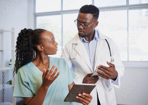 Two Black medical professionals have serious discussion, doctor, nurse, hospital