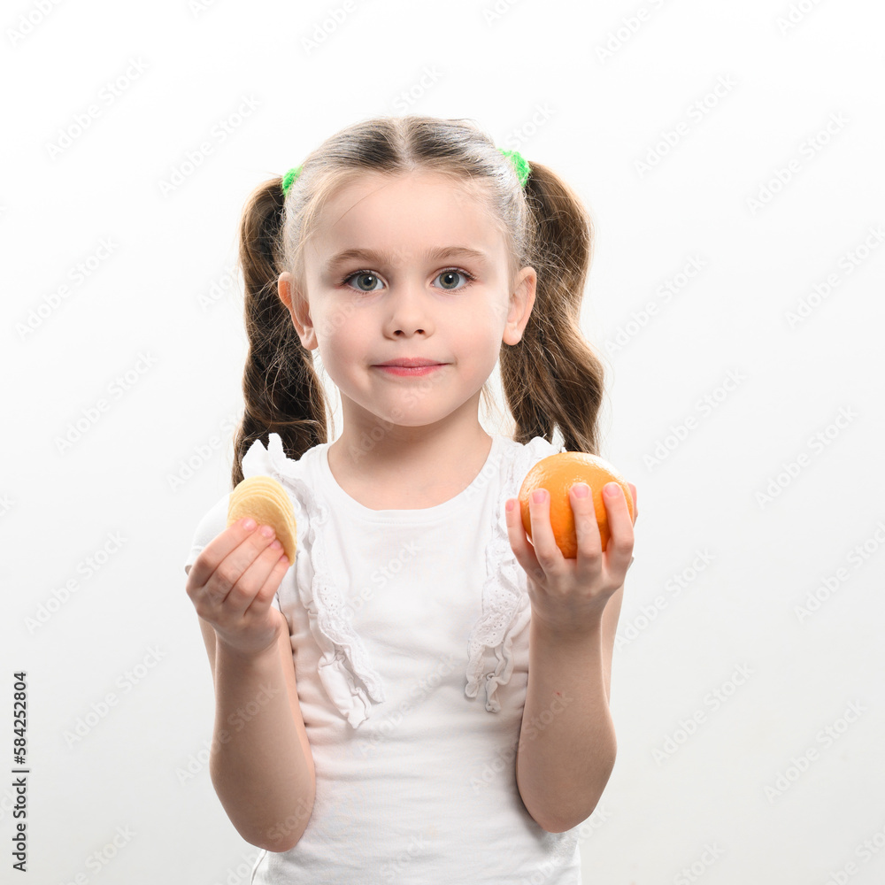 Tangerines and chips, healthy and harmful, a girl with a tangerine and chips in her hands on a white background. Tangerines and chips, healthy and harmful, a girl with a tangerine and chips in her hands on a white background.