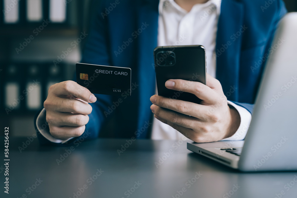 Male businessman use credit cards to conduct financial transactions through phones.