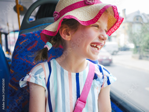 Smiling happy young girl looking out of the window on a bus journey in London, UK
