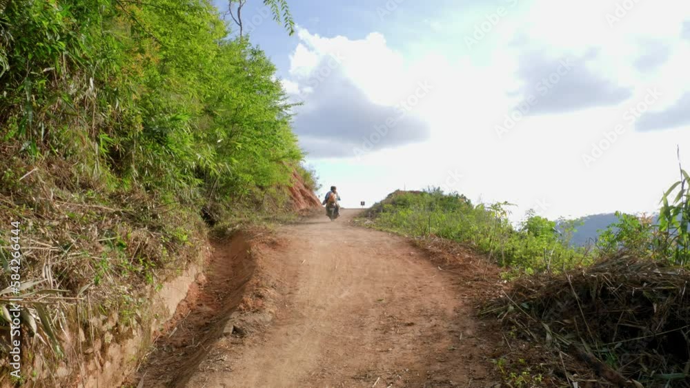 Male and female couple riding moped on dirt road up a mountain on beautiful day, Vietnam Male and female couple riding moped on dirt road up a mountain on beautiful day, Vietnam