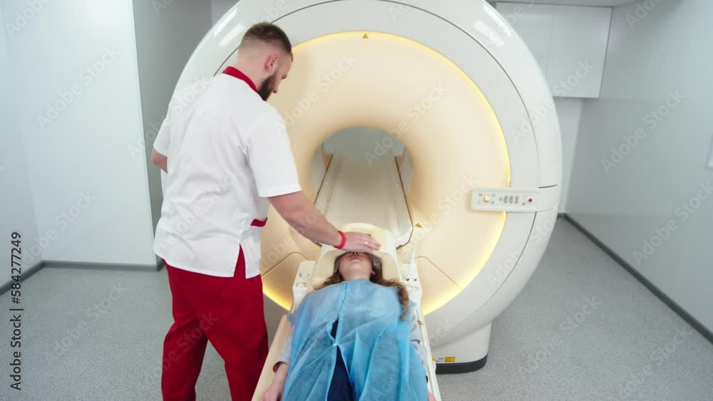 In a medical laboratory, a male radiologist and a female doctor control and monitor an MRI or CT scan with a female patient undergoing a procedure. High-tech modern medical equipment. In a medical laboratory, a male radiologist and a female doctor control and monitor an MRI or CT scan with a female patient undergoing a procedure. High-tech modern medical equipment.