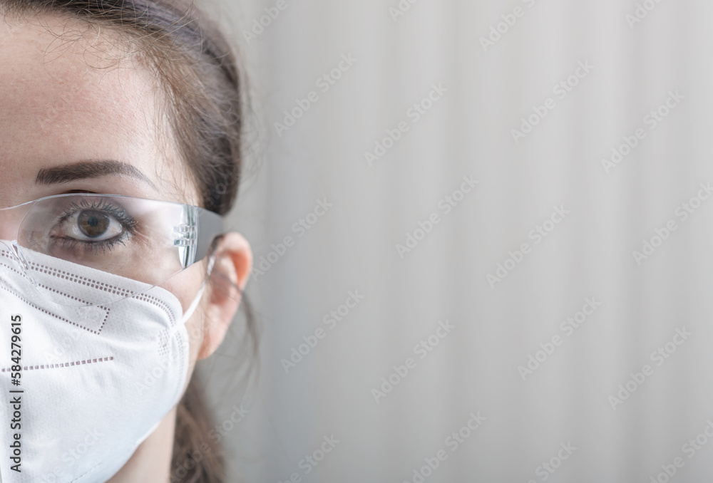 Nurse's close-up half face protrait with protective glasses and N95 mask
