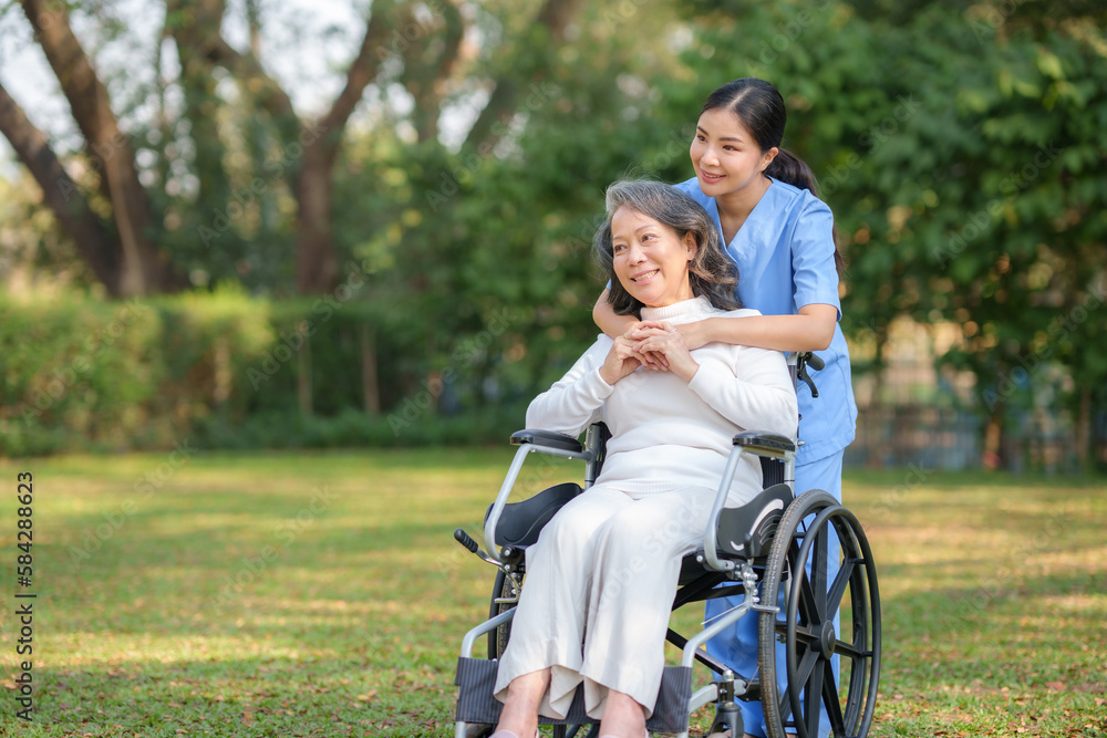 Asian nurse takes a patient in a wheelchair to make her feel refreshed and relaxed at the park. Asian nurse takes a patient in a wheelchair to make her feel refreshed and relaxed at the park.