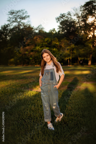 joyful child girl walking in summer park to meet with friends - childhood, leisure and people concept. vertical photo