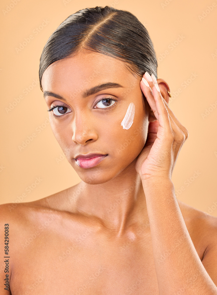 Face portrait, skincare and woman with cream in studio isolated on brown background. Dermatology, serious cosmetics and confident Indian female model with lotion, creme or moisturizer for skin health