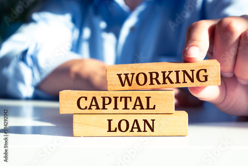 Close up on businessman holding a wooden block with "WORKING CAPITAL LOAN" message