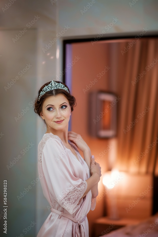 Wedding day. Bride morning. Makeup for the bride. Wedding make-up. Bride portrait. Beautiful young girl. Portrait. Married. Professional makeup. Bride in a diadem. Girl looks at herself in the mirror.