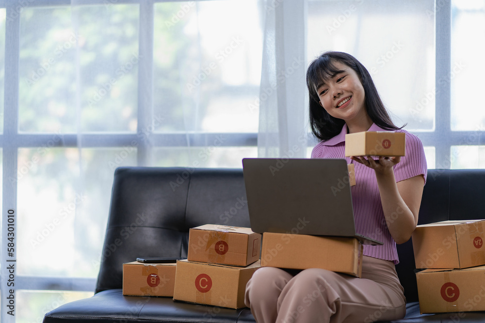 start a small business SME business owners, Asian female entrepreneurs Working box and smartphone laptop on sofa Review online orders to prepare packaging boxes for sale to customers. start a small business SME business owners, Asian female entrepreneurs Working box and smartphone laptop on sofa Review online orders to prepare packaging boxes for sale to customers.