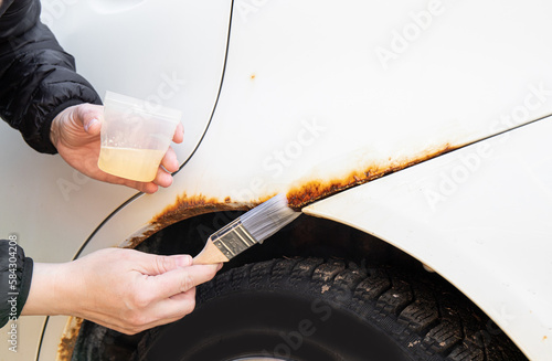 Close up view of person hand apply home use car rust stop liquid on vehicle rusty parts.