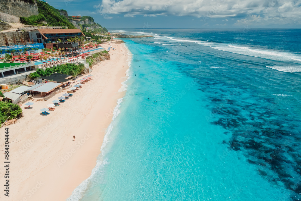 Aerial view of blue transparent ocean and luxury beach with umbrellas in Bali