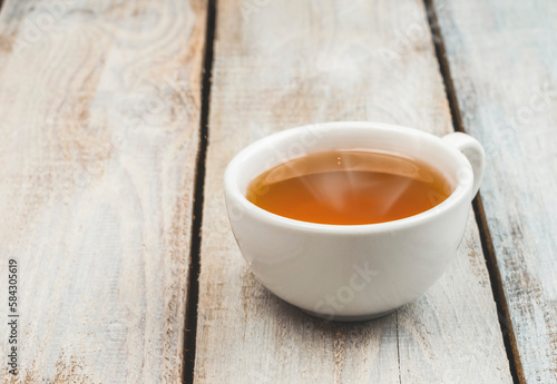 A cup of fragrant hot tea on a light background. Herb tea. Hot drink. White cup with tea.