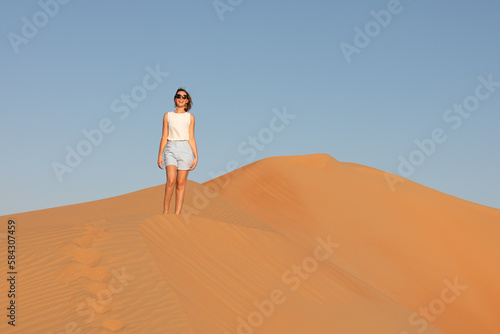 Beautiful young woman posing on the dunes in the desert.