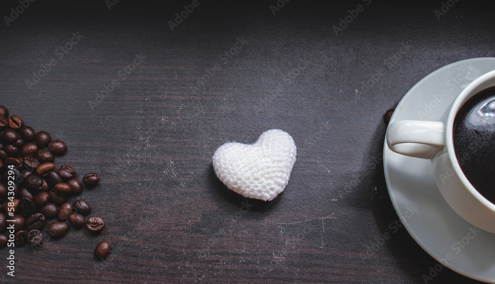 Obraz premium Coffee cup, heart shaped white yarnon on wooden surface