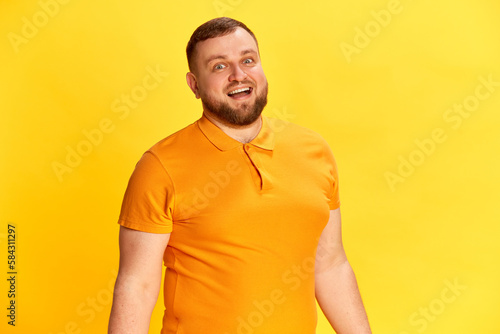 One attractive man smiling and looking at camera with positive facial expression over yellow background. Close up