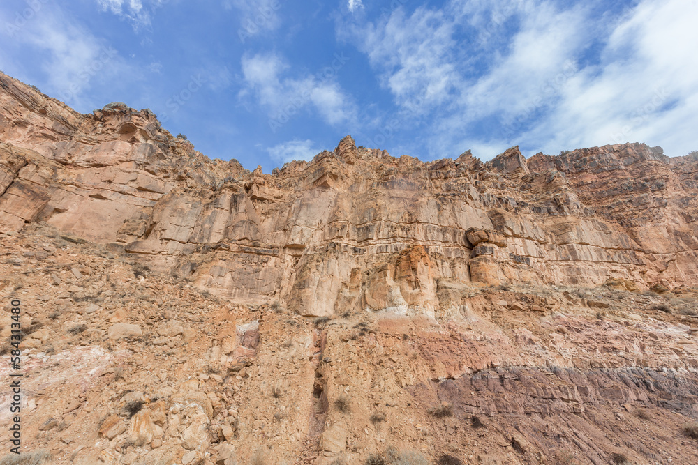 Looking up at a rocky cliff face with blue sky