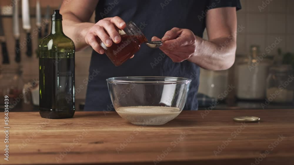Home chef mixing dry yeast with water in a glass mixing bowl. Adding