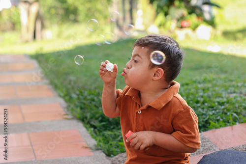 Foto Boy with Down Syndrome Having Fun Blowing Bubbles in His Backyard