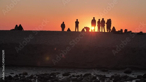 Group of friends having fun watching the sunset at the beach