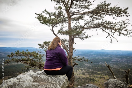 woman sitting on cliff edge after hiking up Cheaha State Park Mountain  highest point in Alabama