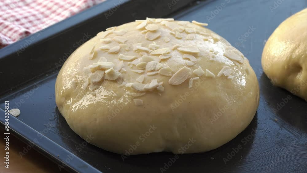 Sprinkling raw mazanec, traditional Czech sweet Easter cake, with sliced almonds Sprinkling raw mazanec, traditional Czech sweet Easter cake, with sliced almonds