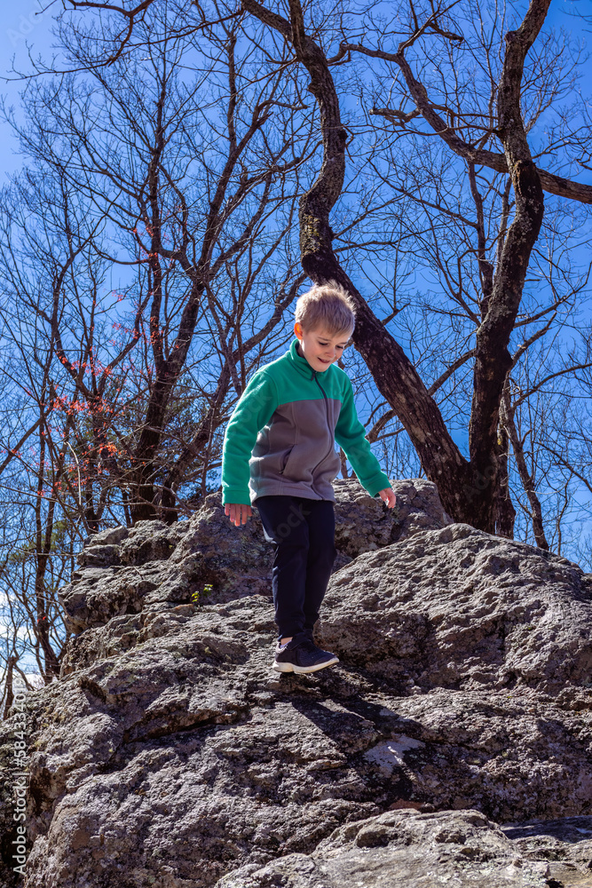 Young boy climbing along rock boulders while hiking up Cheaha mountain in Alabama state park and campground Young boy climbing along rock boulders while hiking up Cheaha mountain in Alabama state park and campground