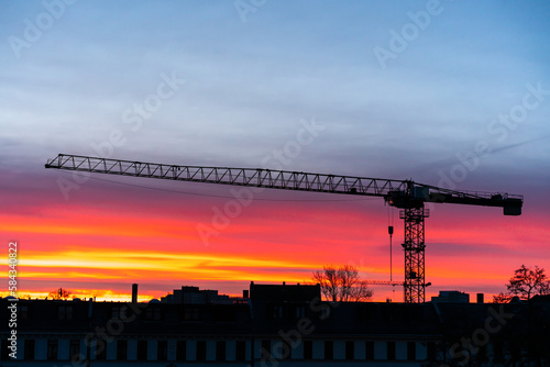 construction crane at sunrise. gradient from red to blue. Full length crane boom.