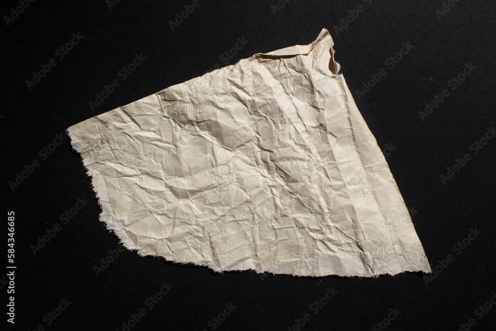 Crumpled torn paper on a black background. Wrinkled ripped paper piece. Crumpled torn paper on a black background. Wrinkled ripped paper piece.
