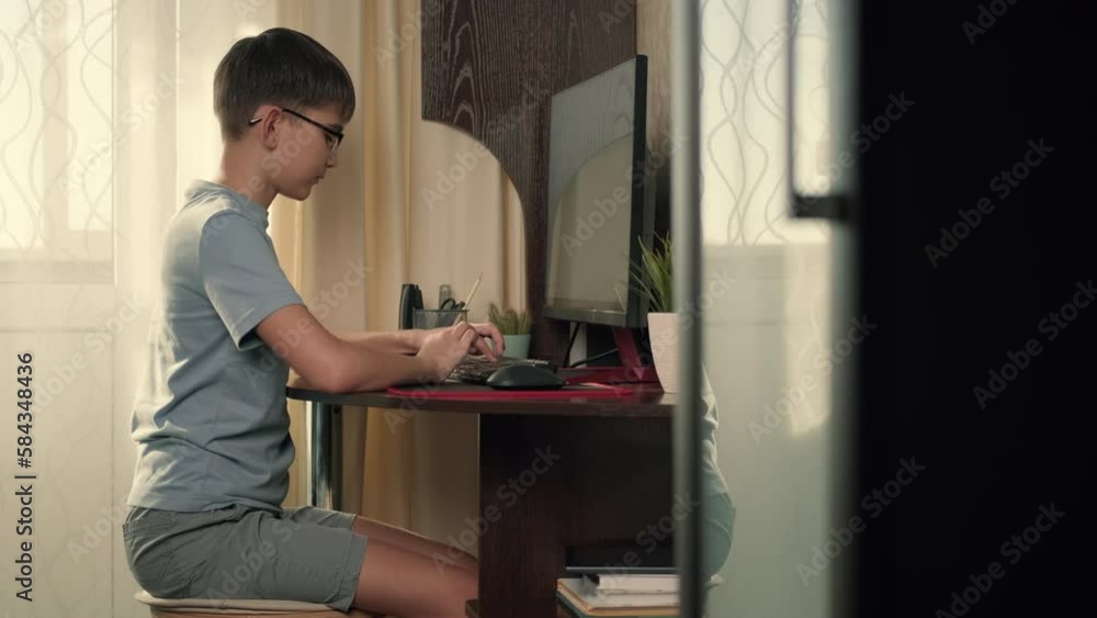 Boy writes program code at home using computer.Authentic Action,Home Window,Sun Flare,Bright Light Boy writes program code at home using computer.Authentic Action,Home Window,Sun Flare,Bright Light