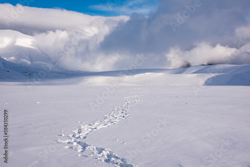 Winter landscape, footprints path in snow valley in bright sunny day