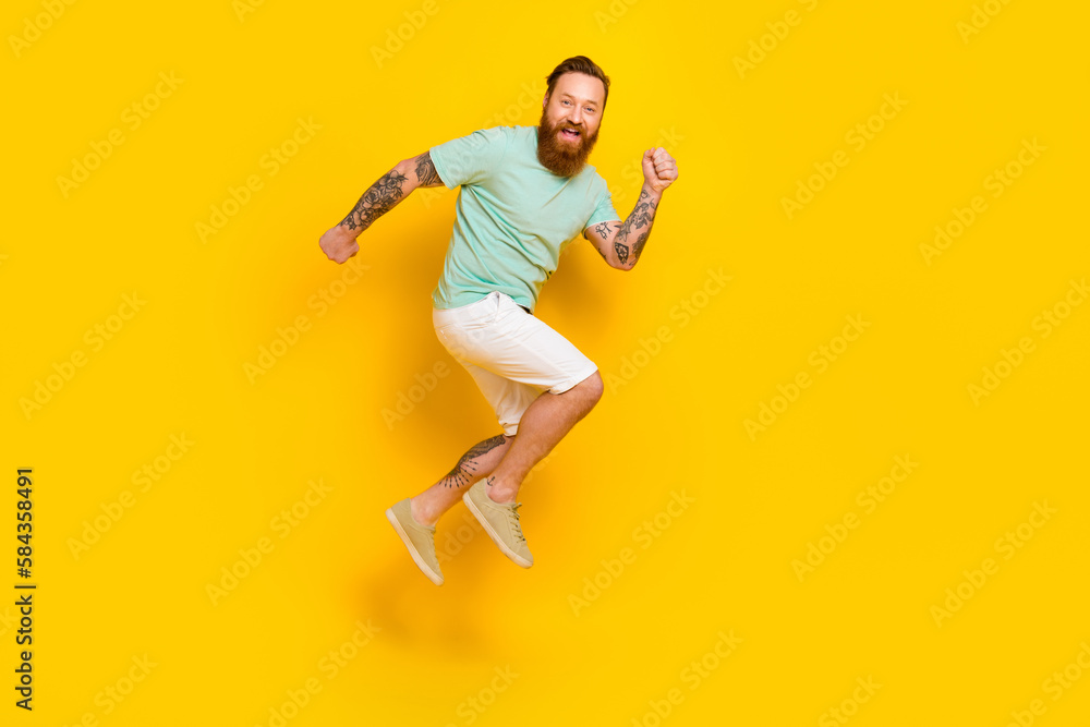 Full length photo of funky running fast speed youngster guy red hairstyle beard wear green t-shirt shopping ad isolated on yellow color background
