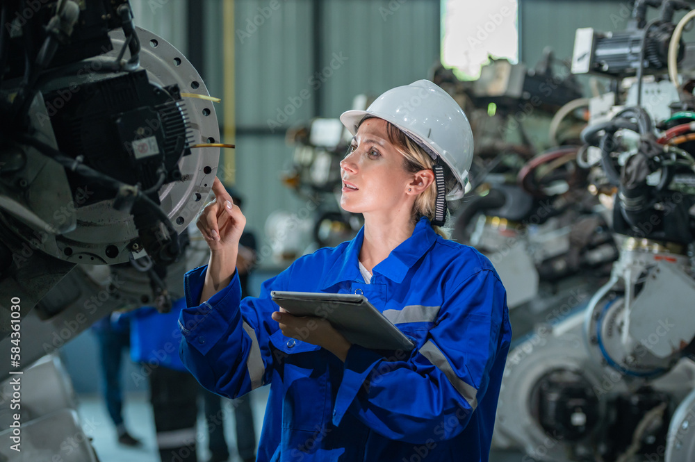 woman engineer in uniform helmet inspection check control heavy machine robot arm construction installation in industrial factory. technician worker check for repair maintenance electronic operation